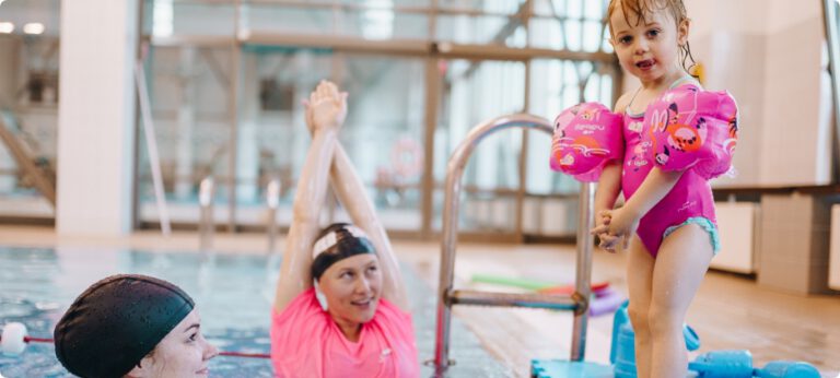 Instruktor pływania Delfinteam pokazuje strzałkę dziecku w basenie